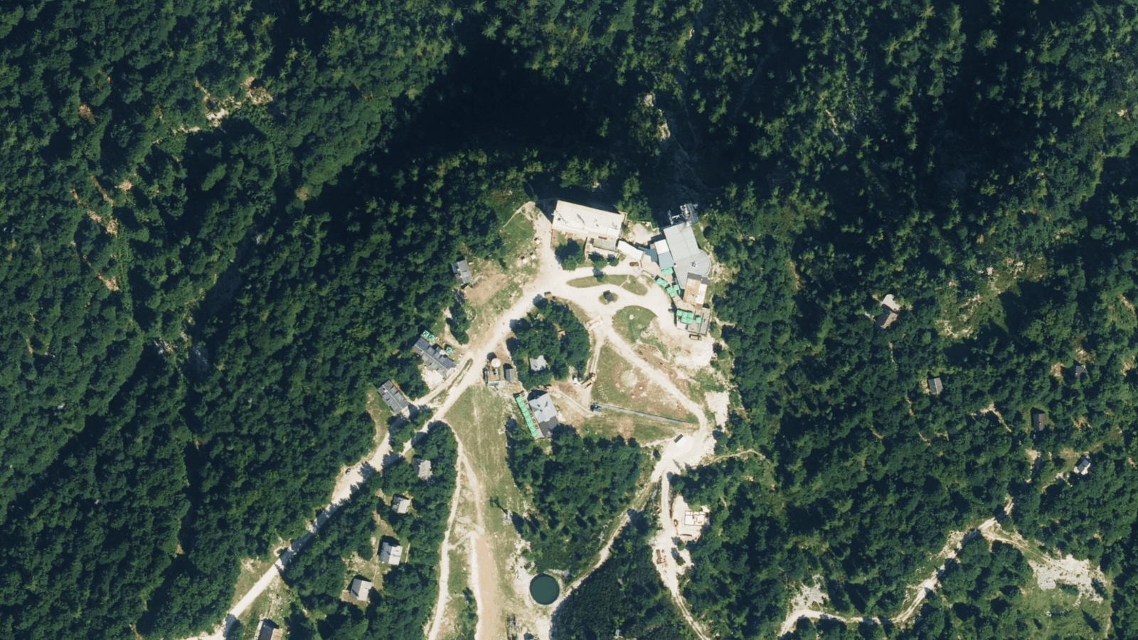 Top-down aerial imagery showing the top station infrastructure and alpine mountain slopes of Vogel Ski Center in Slovenia.